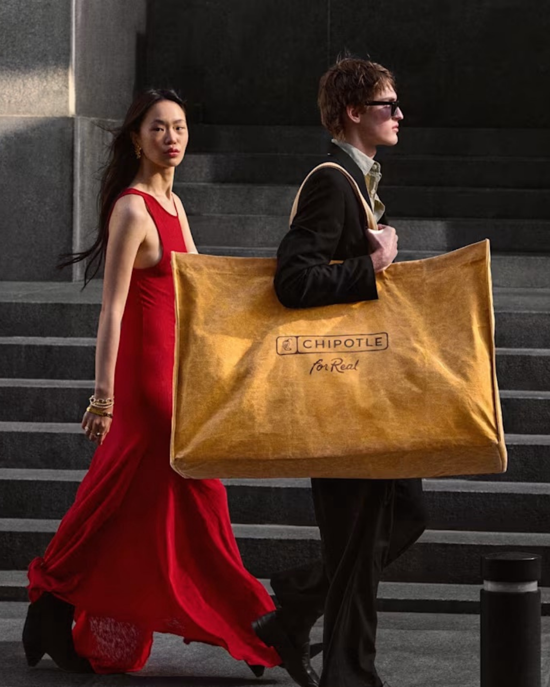 Two people walking together, with one carrying Chipotle's coveted Big Ass Bag.