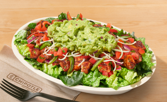 A Chipotle Salad with lettuce, fajita veggies, adobo chicken, fresh tomato salsa, shredded cheese, and topped with fresh hand-mashed guac.